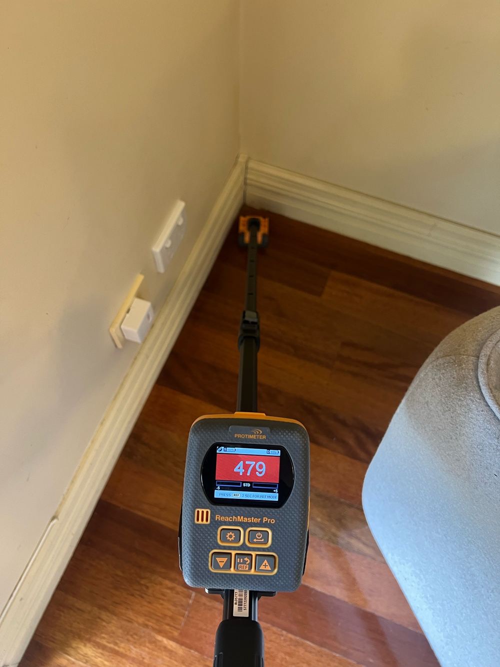 Elevated moisture in a living room corner beside a masonry wall, found during a pre-purchase inspection in Newport